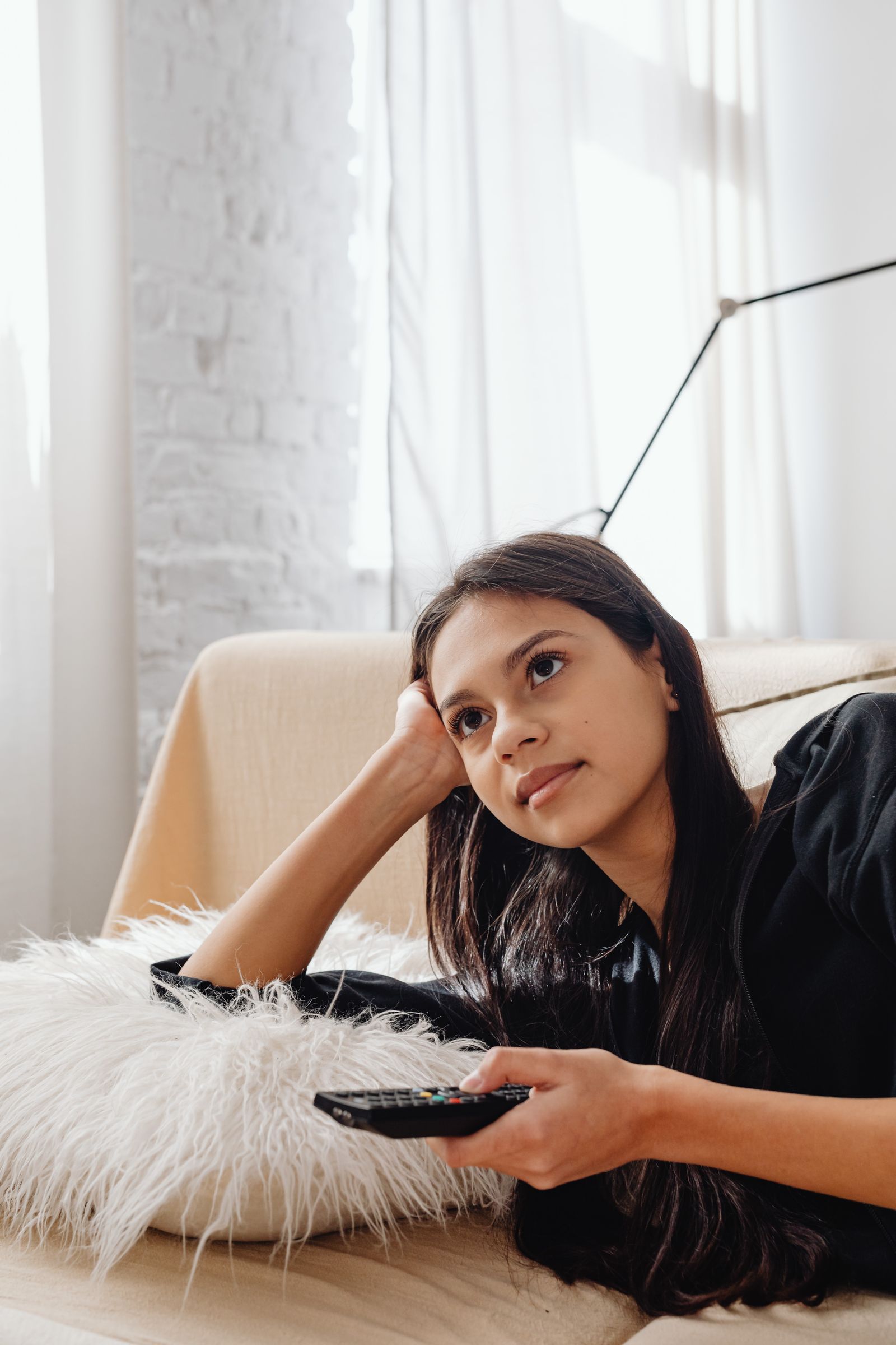 Viewer holding a remote control while watching television at home